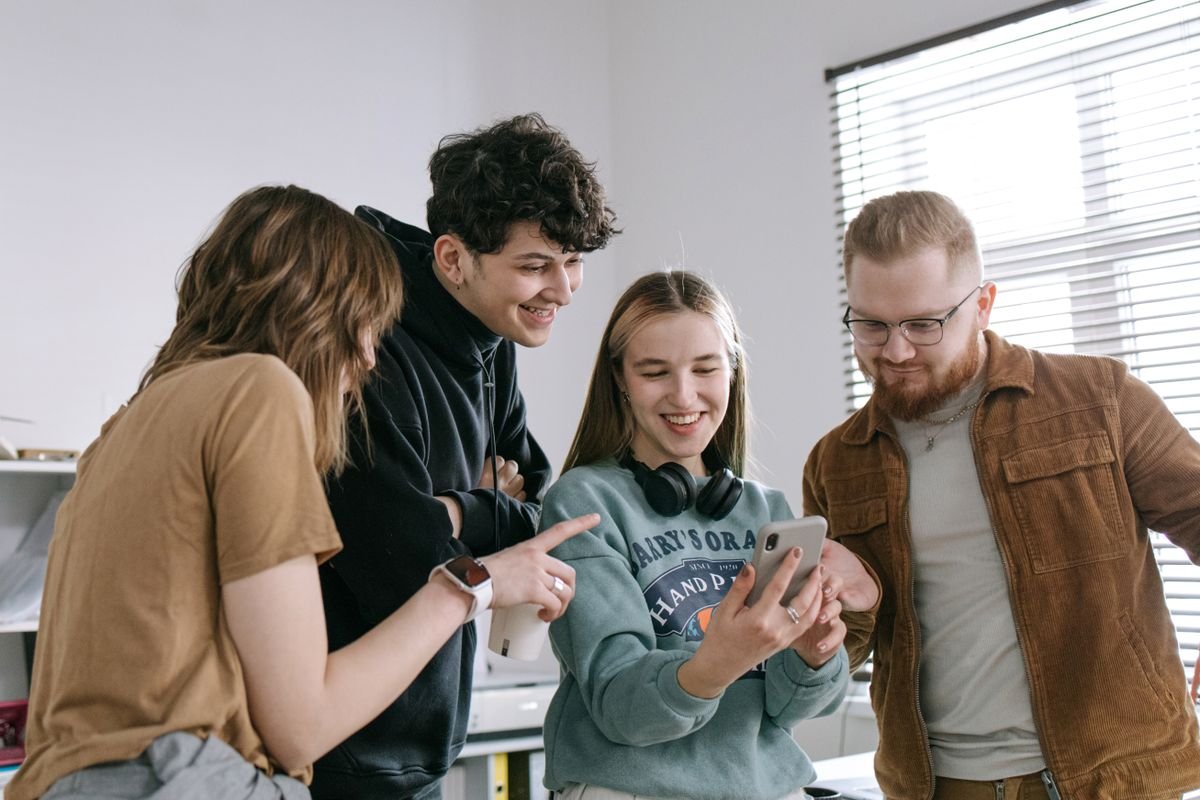 Collega's lachen om iets op een telefoon achter de balie
